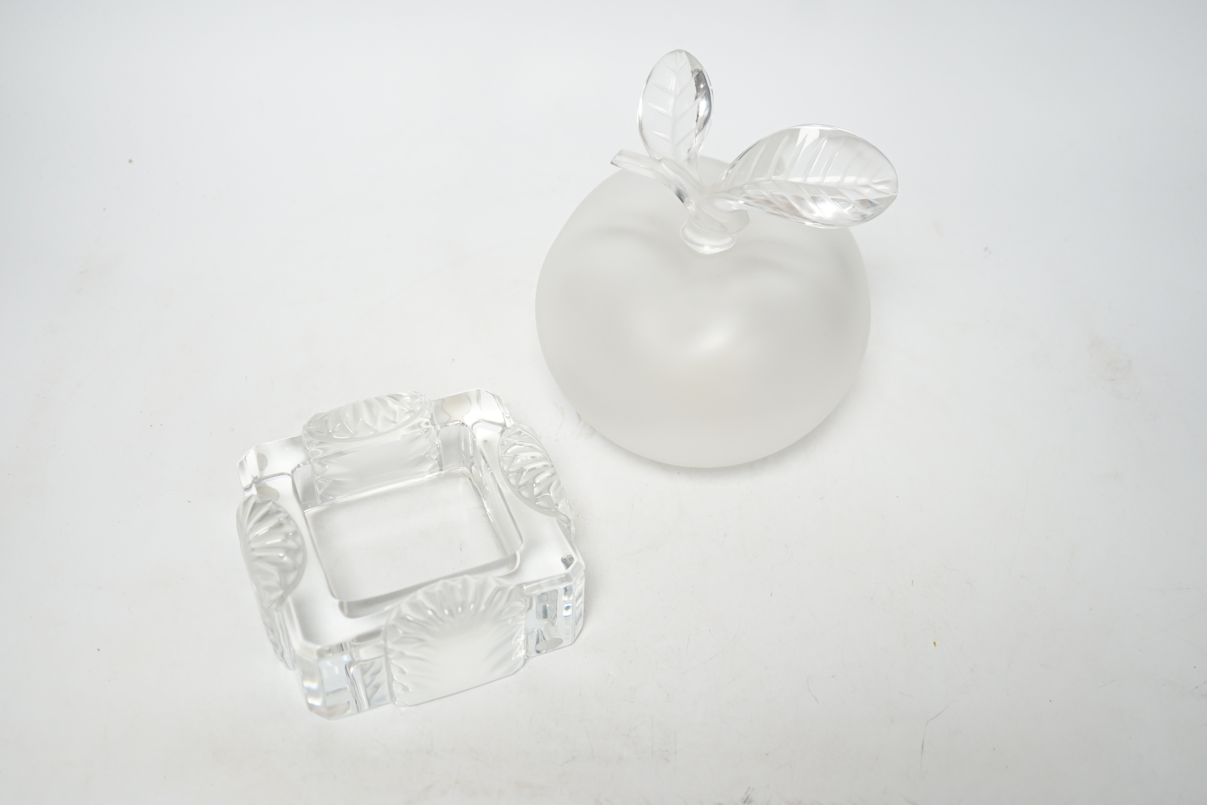 A Lalique apple shaped perfume bottle and leaf stopper together with a square ashtray, both with signed engraving to base, perfume bottle 14cm high